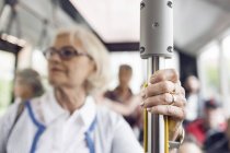Senior woman holding handrail in bus — Stock Photo
