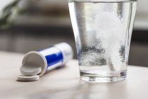 Close-up de vidro de água e medicina em cima da mesa — Fotografia de Stock