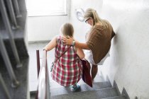 Madre e hija con síndrome de Down bajando escaleras - foto de stock