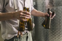 Mitarbeiter der Brauerei hält leere Bierflaschen in der Hand — Stockfoto