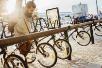Homem tomando bicicleta alugada fora do rack na estação — Fotografia de Stock