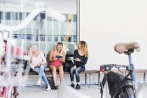 Drei junge Frauen sitzen auf Bank — Stockfoto