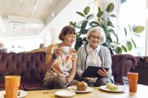 Дві жінки використовують цифровий планшет у кафе — стокове фото