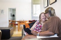 Мать и дочь с синдромом Дауна сидят на диване — стоковое фото