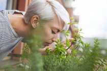 Mulher cheirando ervas frescas na varanda — Fotografia de Stock