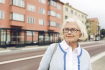 Woman standing next to bus stop and looking away — Stock Photo