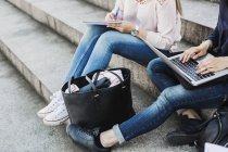 Молодая женщина с ноутбуком, сидя на ступеньках — стоковое фото