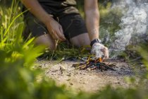 Hombre encendiendo fuego de campamento en tierra - foto de stock