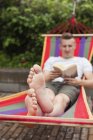 Mann liest tagsüber Buch auf Hängematte — Stockfoto