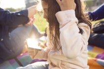 Батьки з дочкою (4-5) на пікніку в місті, дочка використовує смартфон — стокове фото