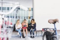 Drei junge Frauen sitzen auf Bank — Stockfoto