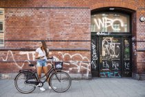 Ragazza adolescente (14-15) in piedi sul marciapiede con la bicicletta — Foto stock