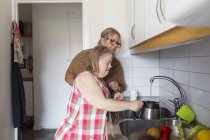 Madre e hija con síndrome de Down en la cocina - foto de stock