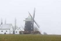 Paisaje rural con molino de viento en día de niebla - foto de stock