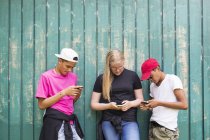 Menina adolescente e meninos adolescentes (14-15) usando telefones inteligentes — Fotografia de Stock