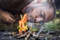 Homem acendendo fogo acampamento na floresta durante o dia — Fotografia de Stock