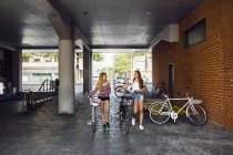 Дві дівчини-підлітки (14-15) ходять з велосипедами — стокове фото