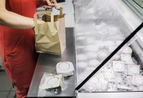 Vendedor embalaje queso en bolsa de papel - foto de stock