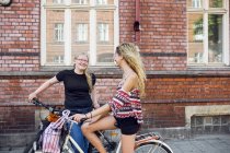Two teenage girls (14-15) on bicycles talking — Stock Photo