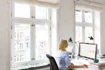 Жінка працює на комп'ютері в офісі — стокове фото