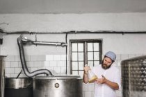 Работник пивоваренного завода рассматривает пиво в стакане — стоковое фото