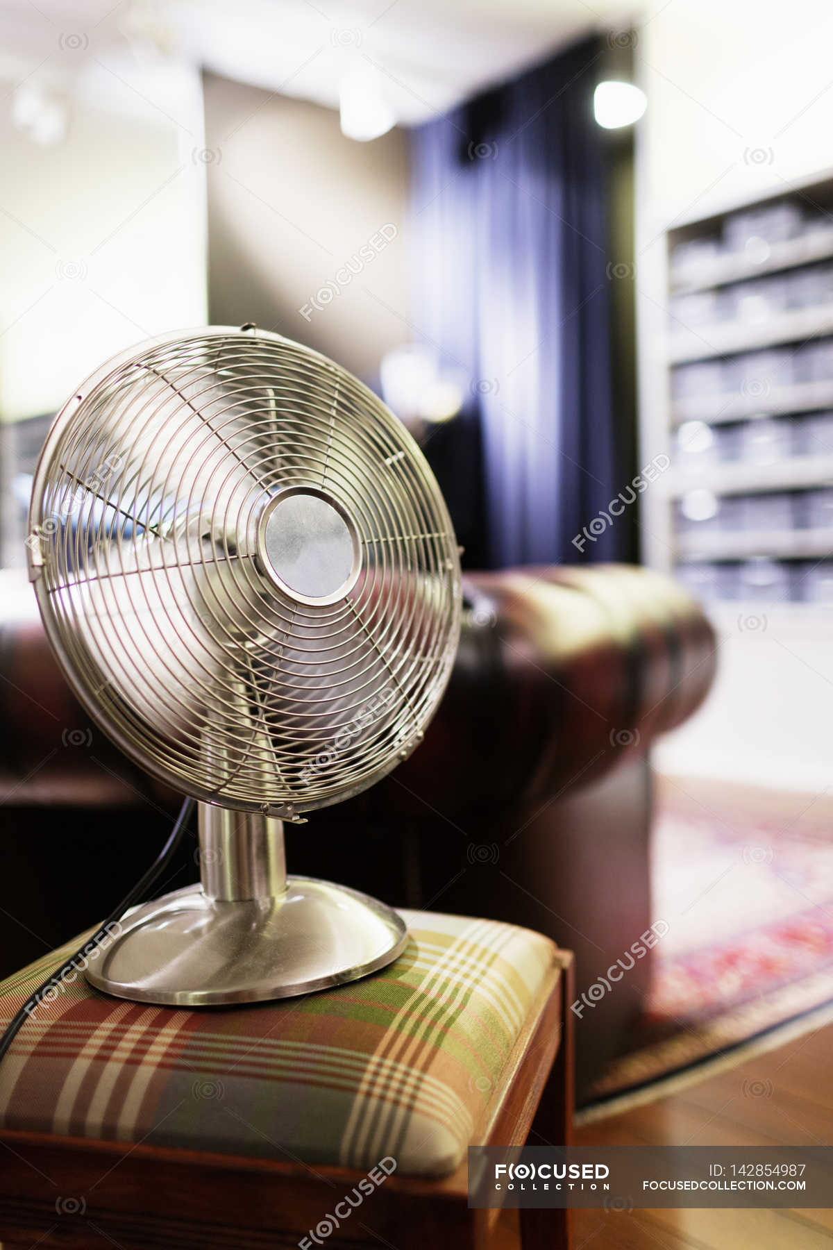 Electric fan on stool in clothing store — showroom, vertical Stock