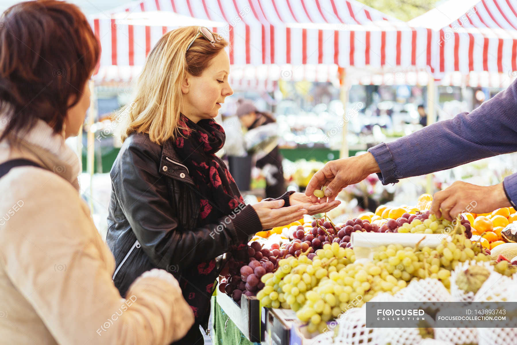 Mature woman buying grapes — selective focus, choosing Stock Photo