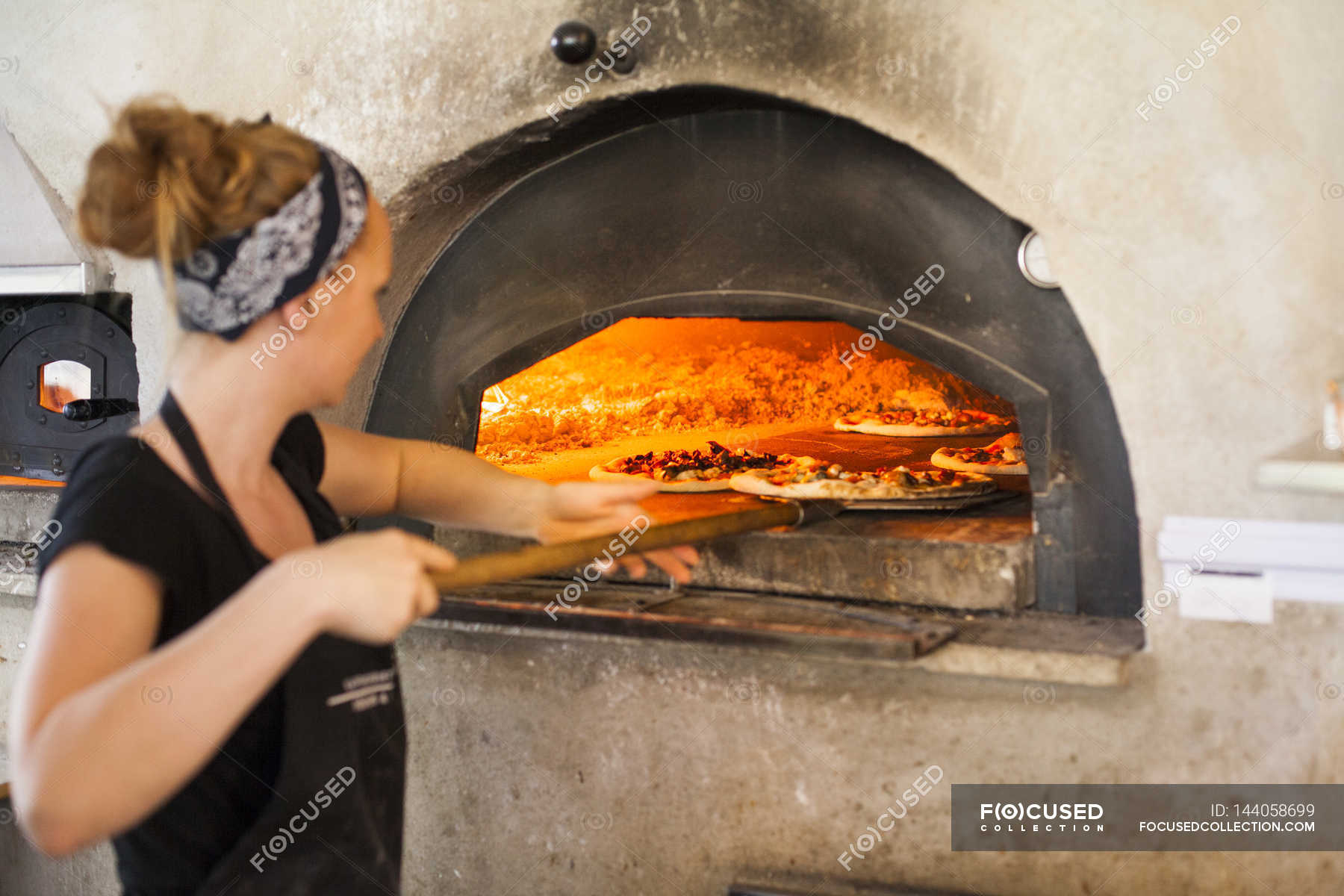 Chef putting pizza in oven — working, female - Stock Photo | #144058699