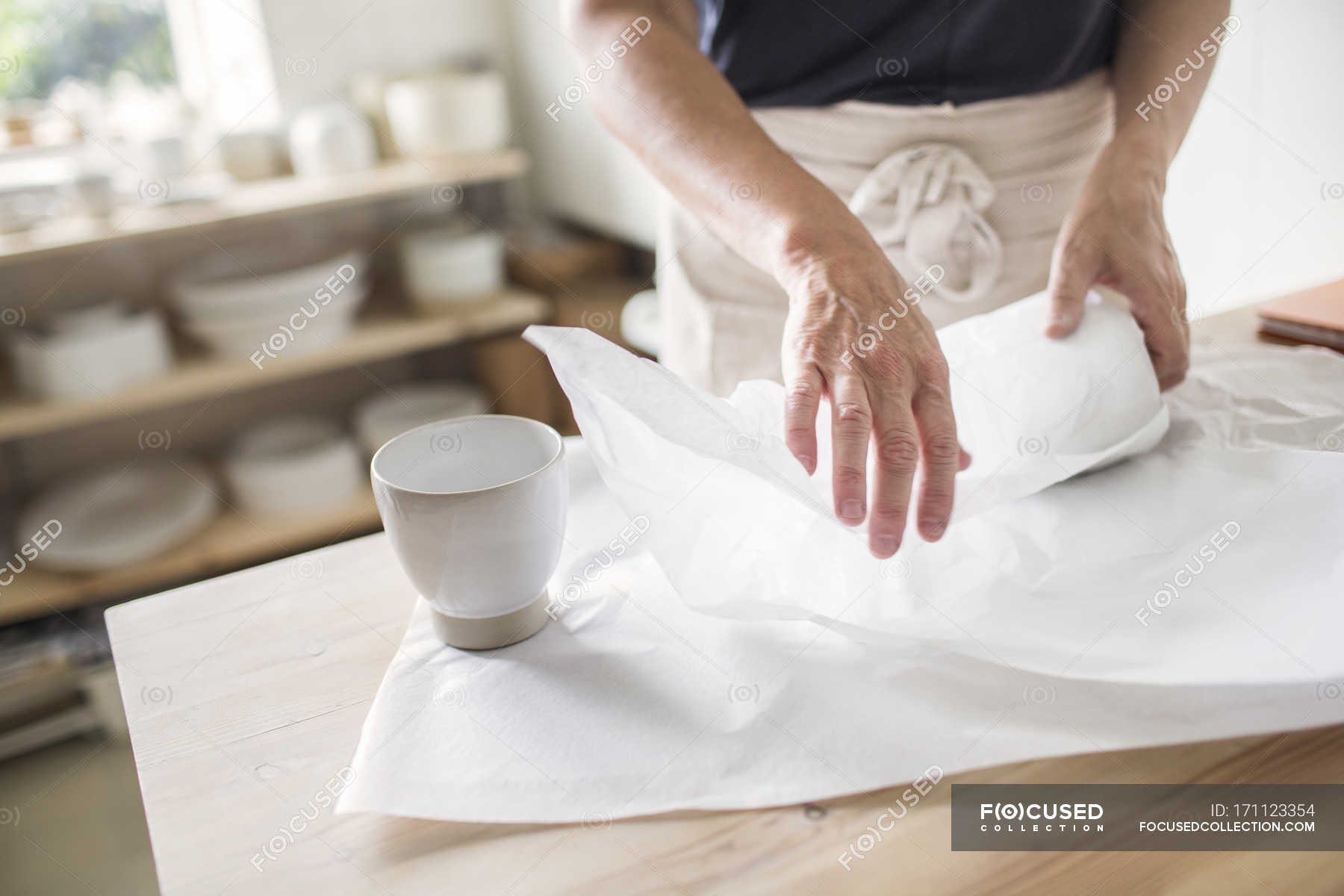 Potter wrapping pottery in paper — artist, craft Stock Photo 171123354