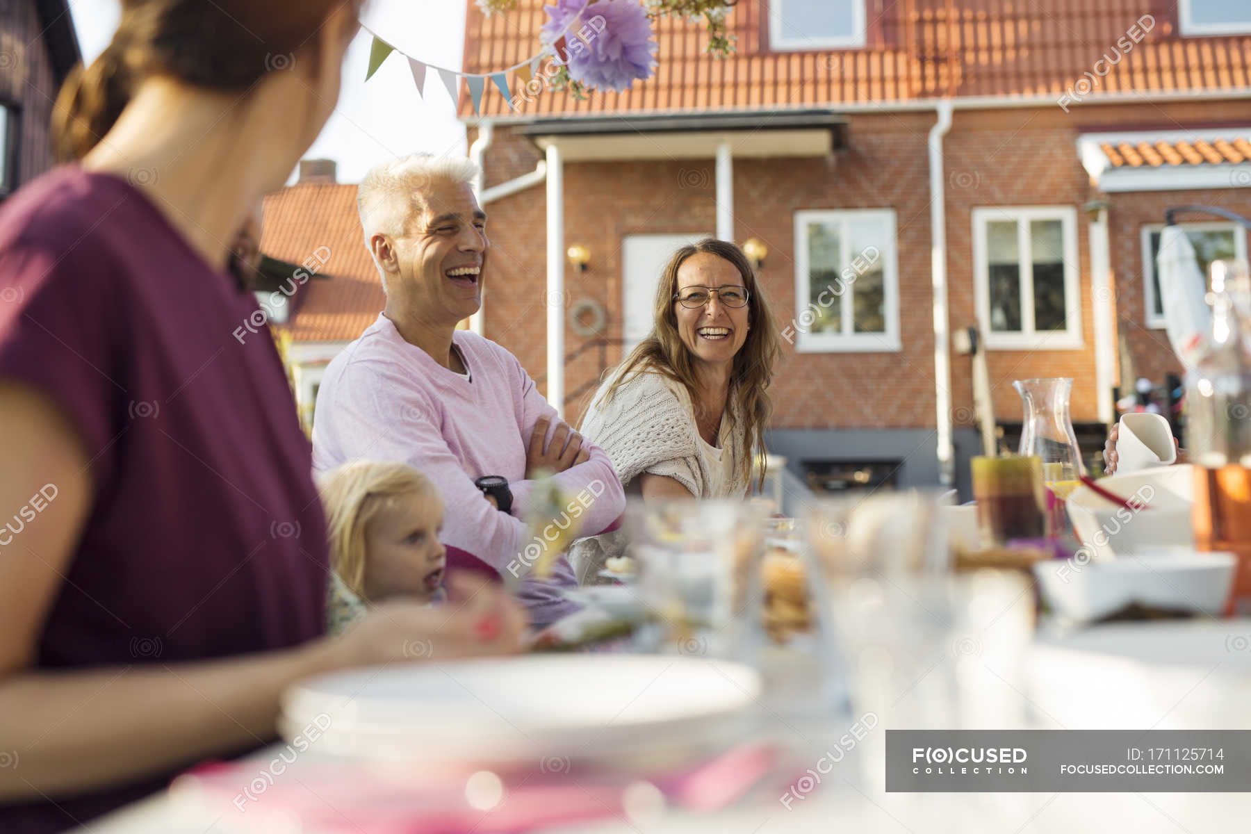 Family sitting at dinner table at garden party in back yard — candid ...