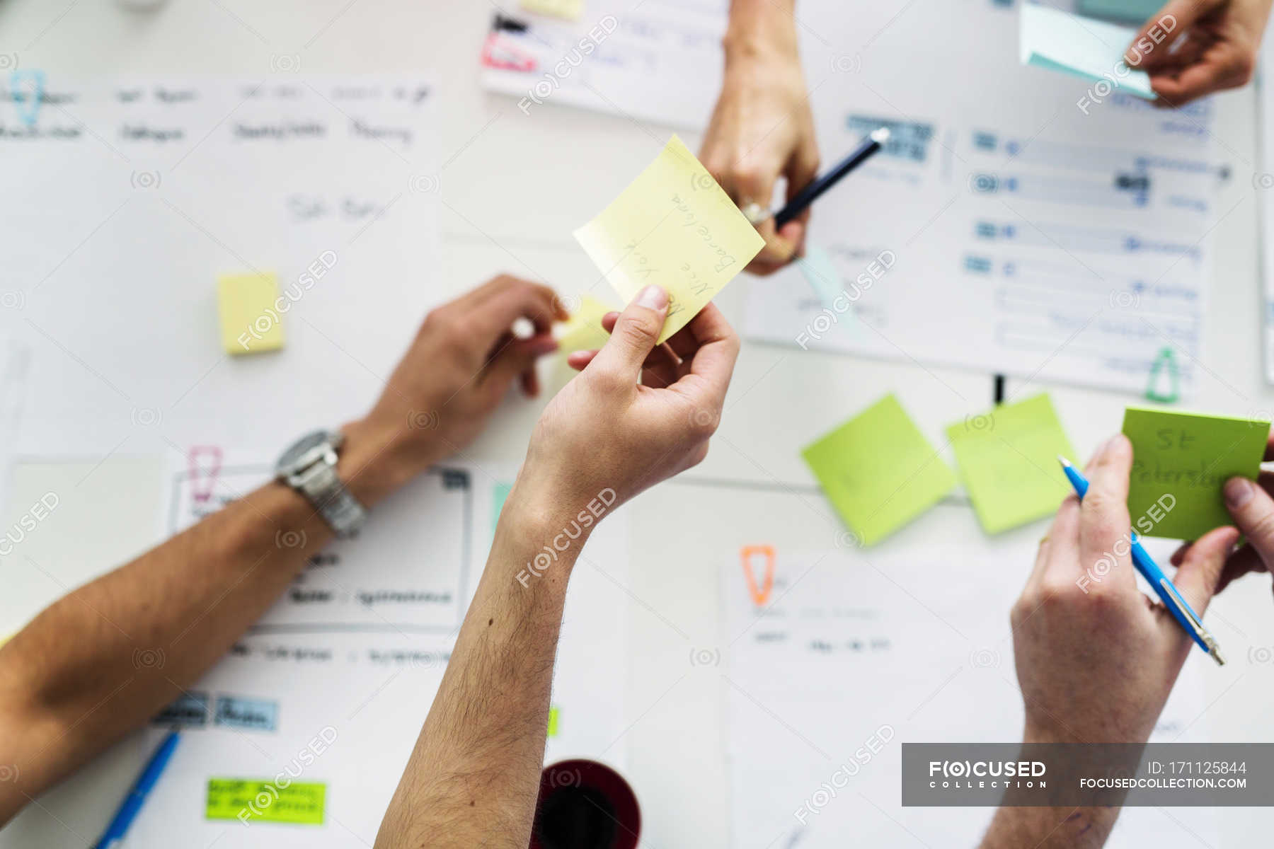 Top view of colleagues using adhesive notes during business meeting ...