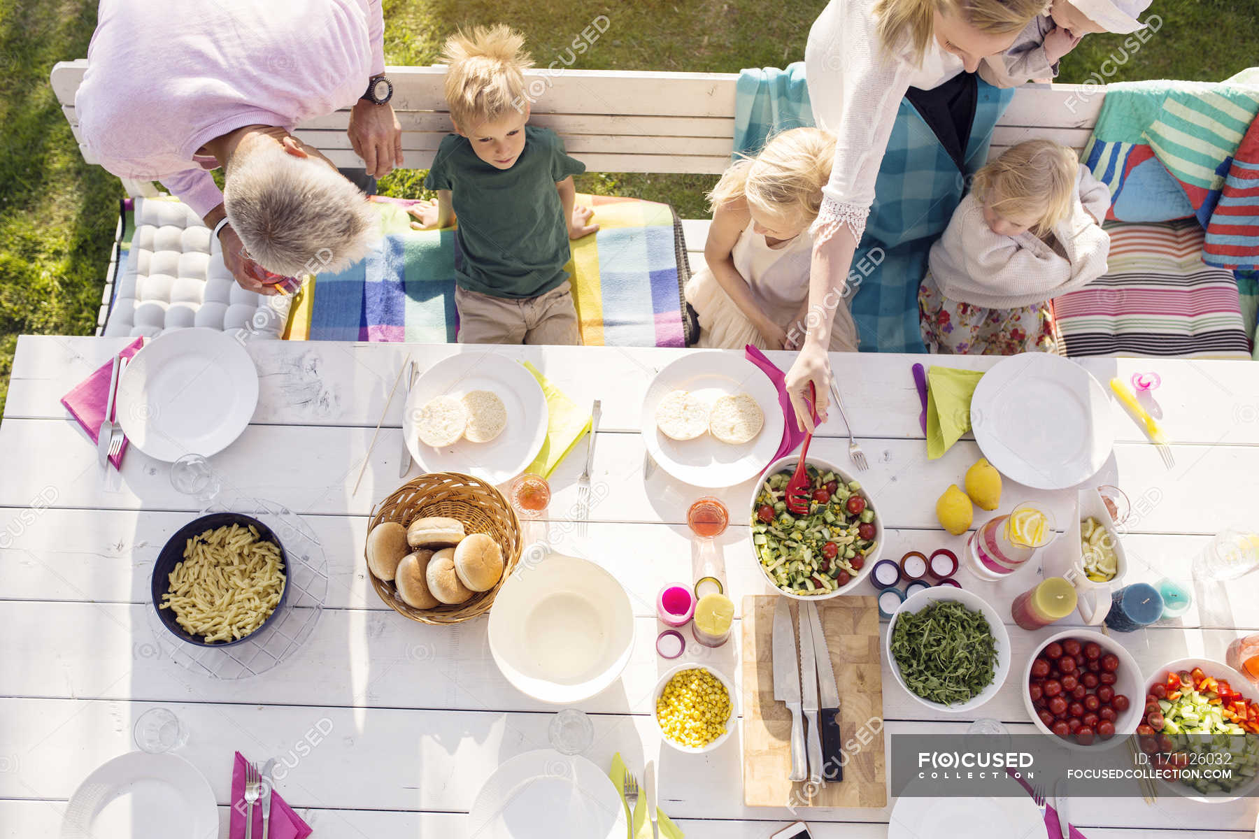 Top view of family sitting at dinner table at garden party in back yard ...