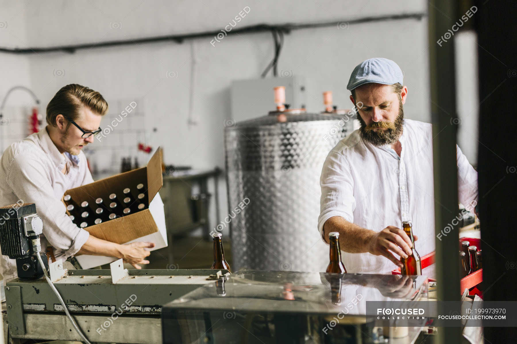 Brewery workers putting beer bottles into boxes — selective focus