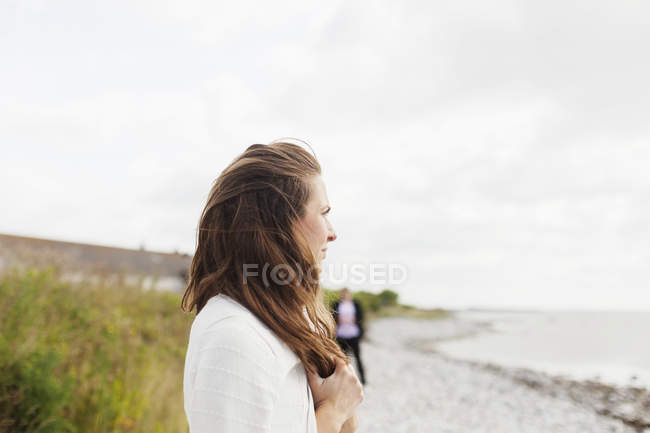 Жінка стоїть на пляжі проти неба — стокове фото