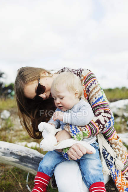 Madre e hijo sentados en la playa - foto de stock