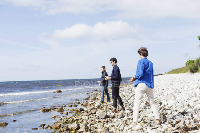 Amigos sosteniendo guijarros en la playa - foto de stock