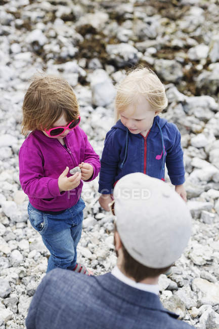 Padre e hijas de pie en la playa - foto de stock