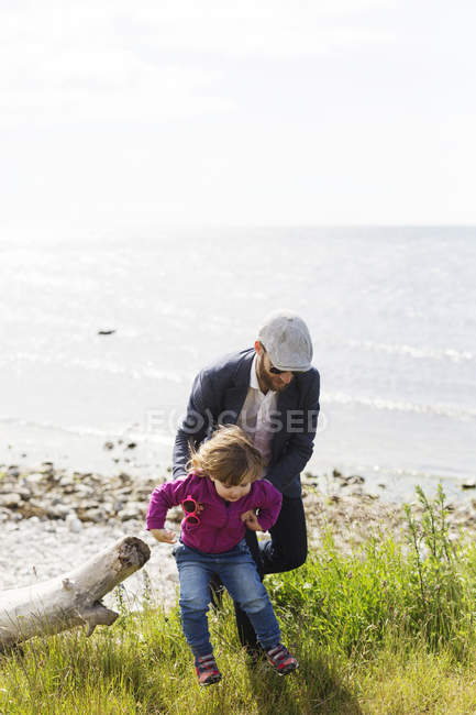 Pai segurando filha na praia — Fotografia de Stock