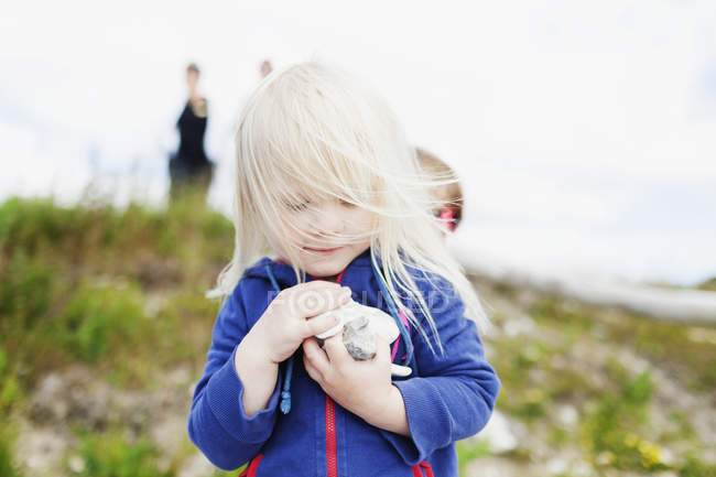 Девушка держит камешки на поле — стоковое фото