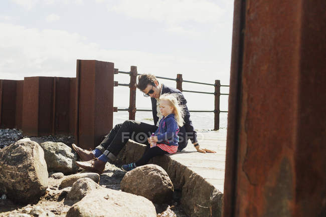 Father and daughter sitting on pier — Stock Photo