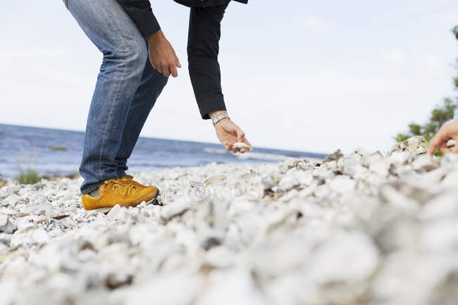 Uomo raccogliendo pietre in spiaggia — Foto stock