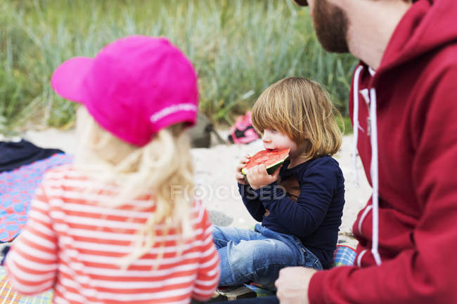 Familia disfrutando de picnic en la playa - foto de stock