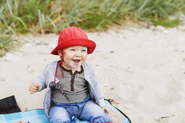 Bambino sorridente seduto in spiaggia — Foto stock