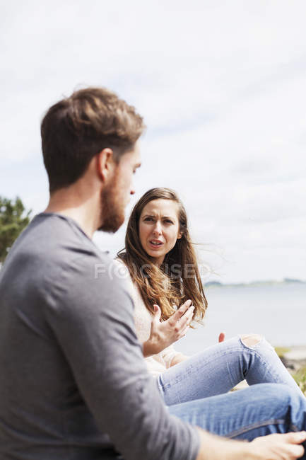 Hombre y mujer sentados y hablando - foto de stock