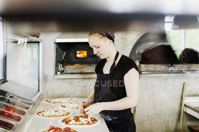 Женщина-шеф-повар делает пиццу — стоковое фото