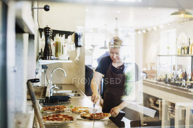 Chef mujer cortando pizza - foto de stock