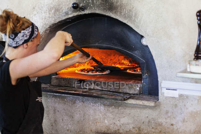 Женщина расплющивает пиццу — стоковое фото