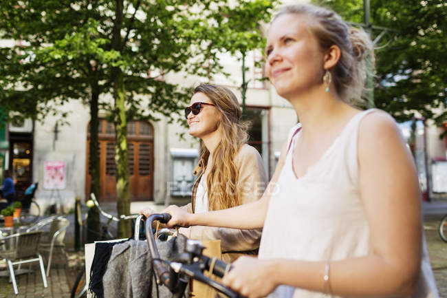 Женщины-подруги с велосипедом и сумками — стоковое фото