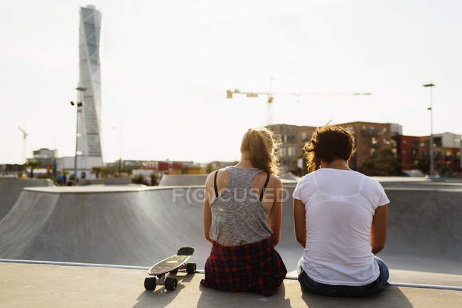 Amigos sentados en el borde de la rampa de skate - foto de stock