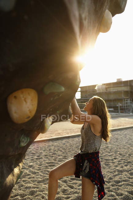 Girl climbing up artificial rock — Stock Photo